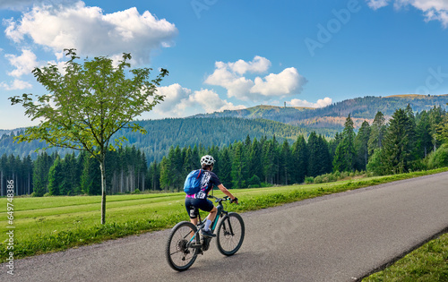 nice senior woman on her electric mountain bike cycling in the German Black Forest below Feldberg summit in Baden-Wuerttemberg, Germany