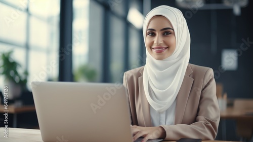 Young Muslim woman wearing a hijab is working on a laptop in the office