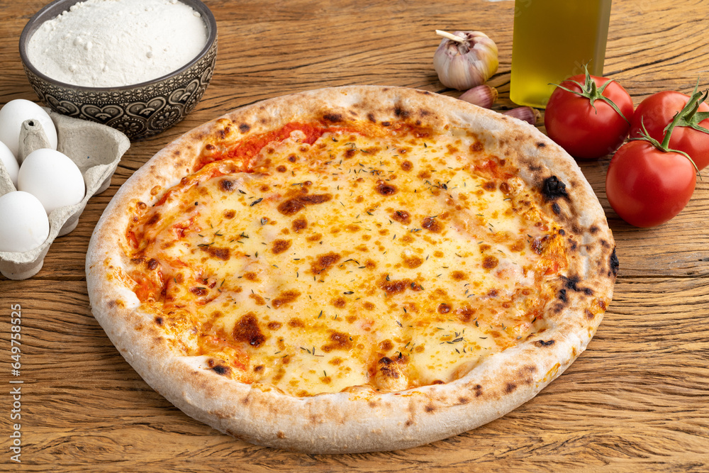 Mozzarella cheese pizza with tomatoes, eggs and flour over wooden table Mozzarella cheese pizza with tomatoes, eggs and flour over wooden table