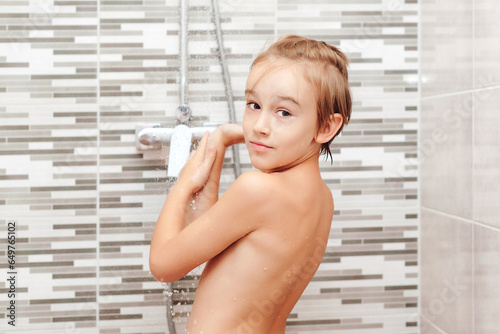 Happy boy having a shower in bathroom.