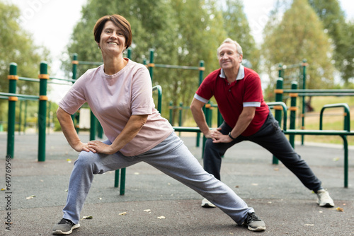 Married couple performs gymnastic exercises together on a sports field photo