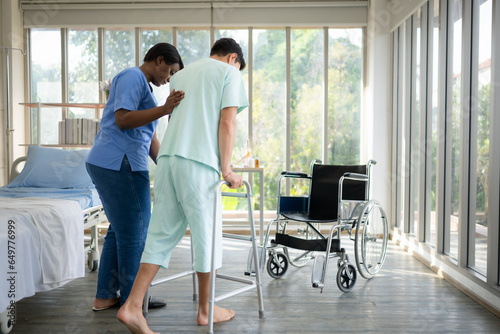 Schilderij op canvas Young female nurse helping young male patient to walk on walker at patient room