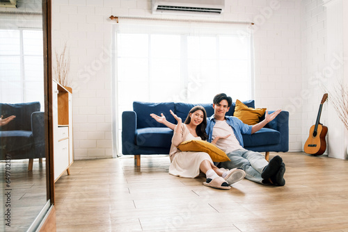 Attractive new marriage man and woman sit on the floor together and feel happy in the living room at the new home. A family spends quality time together after moving into a new home.