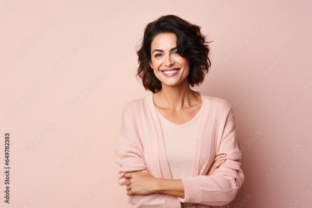 Joyful woman with curly hair smiling in pink studio portrait