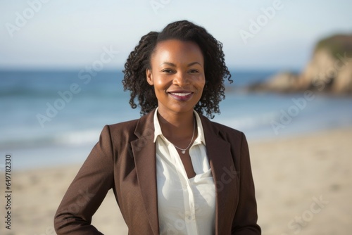 Cheerful woman with curly hair smiling at camera on the beach