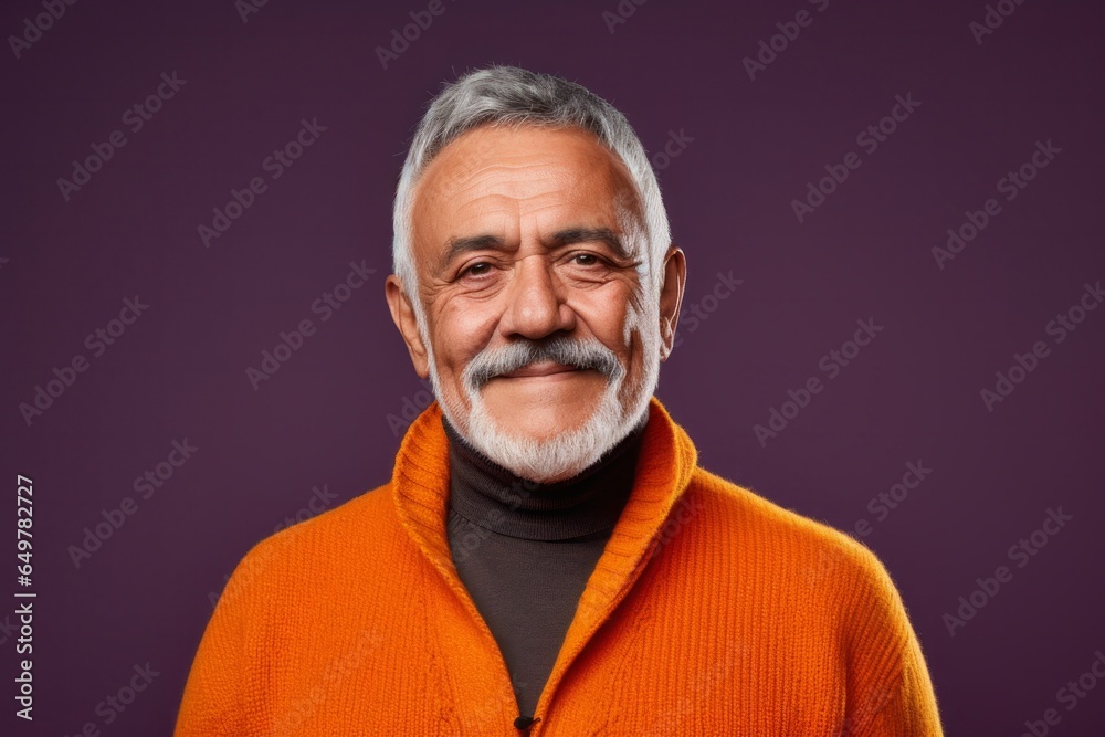 Smiling senior in business attire with gray beard and sweater, looking confidently at camera indoors Smiling senior in business attire with gray beard and sweater, looking confidently at camera indoors