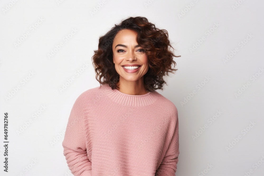 Cheerful woman with curly hair and pink sweater standing on white background