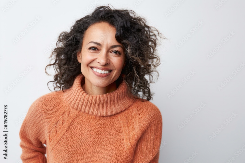 Cheerful mature woman with curly brown hair smiling happily at the camera in studio portrait