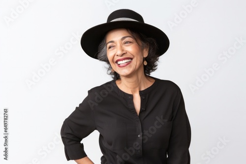 Joyful woman with a happy smile, wearing a hat and white clothing, looking at camera on a white background