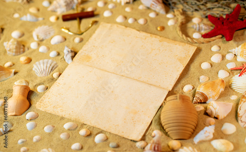 Beach theme. Vintge sheet of paper on the sand among shells, stones and marine elments. Frame on the sand background photo