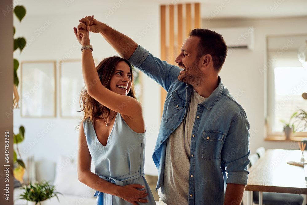 Fototapeta premium Romantic couple dancing in the living room, feeling energetic.