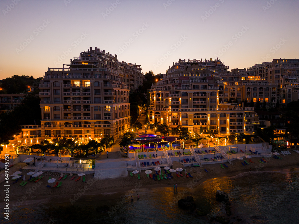 Obraz premium At night, a drone unveils a luxurious seaside hotel on Bulgaria's coast. Lights craft a magical ambiance of warmth and luxury.