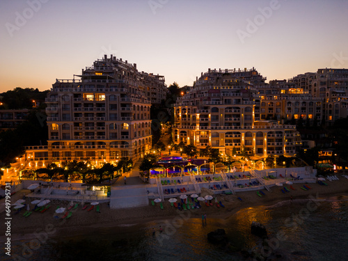 At night, a drone unveils a luxurious seaside hotel on Bulgaria's coast. Lights craft a magical ambiance of warmth and luxury.