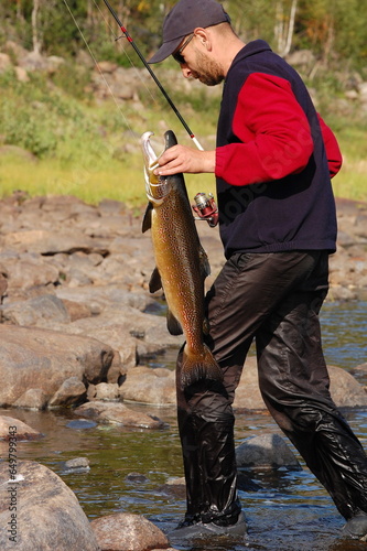 Fisherman carries a large male salmon.