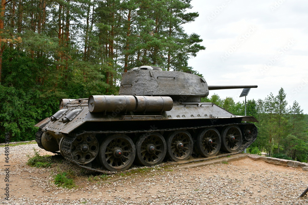 A close up on a massive tank on wheels with its long barrel used for shooting pointing towards the bottom of a tall hill standing in the middle of a forest or moor spotted on a Polish countryside