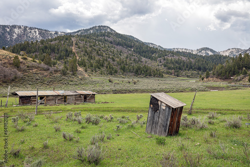 Deserted, abandoned ranch building and out-house in the foothills of the Colorado Rocky Mountains in spring.   photo