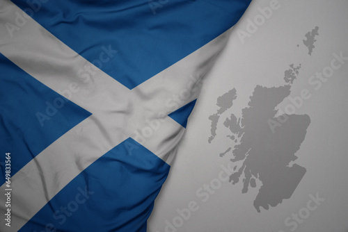 big waving national colorful flag and map of scotland on the gray background. photo