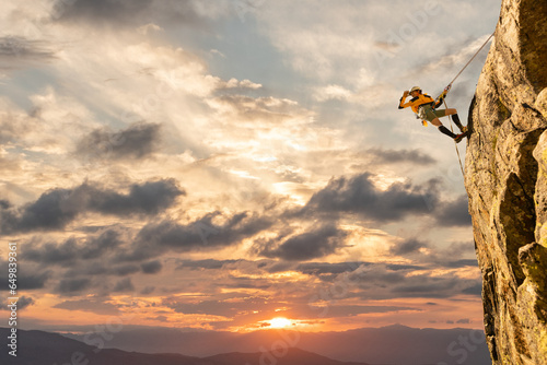 Woman climbing at sunset on mountain golden colors, feeling security and confidence