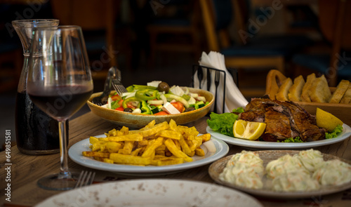 traditional albanian food. restaurant dinner. baked lamb meat with salad, tzatziki and potatoes
