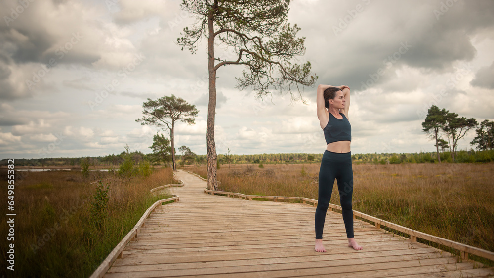 Fit, sporty woman doing an arm stretch exercise outside on a boardwalk