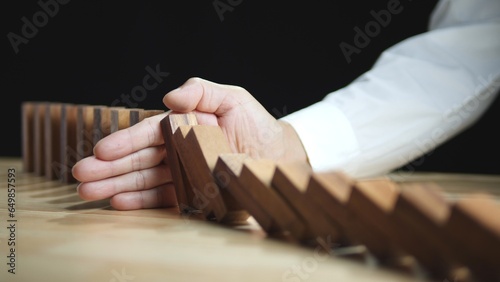 Business Risk Management Concept. Businessman hand stopping wooden domino protect business crisis effect. Concept of Business Crisis, Risk, Management, Assessment, Insurance, Financial, Economic