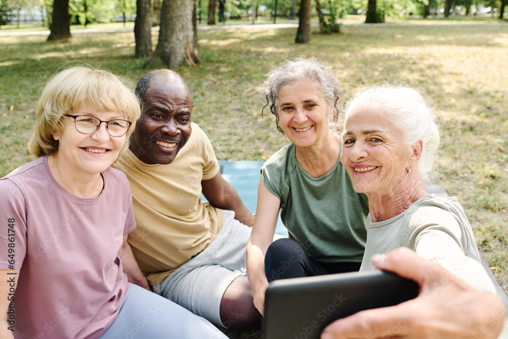 Senior people making selfie portrait on smartphone while sitting in the park Senior people making selfie portrait on smartphone while sitting in the park