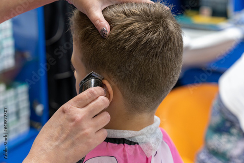Hair cutting for a child using a hair clipper in a beauty salon