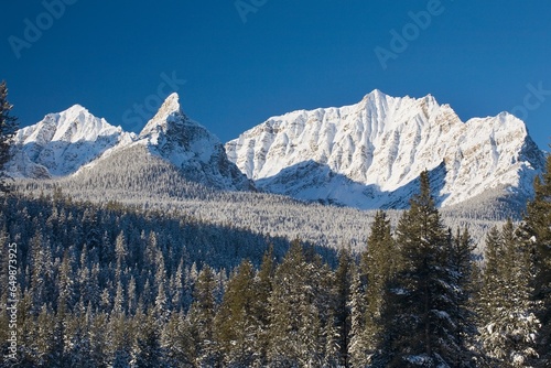 Snow Covered Mountain Range Against A Deep Blue Sky; Banff, Alberta, Canada