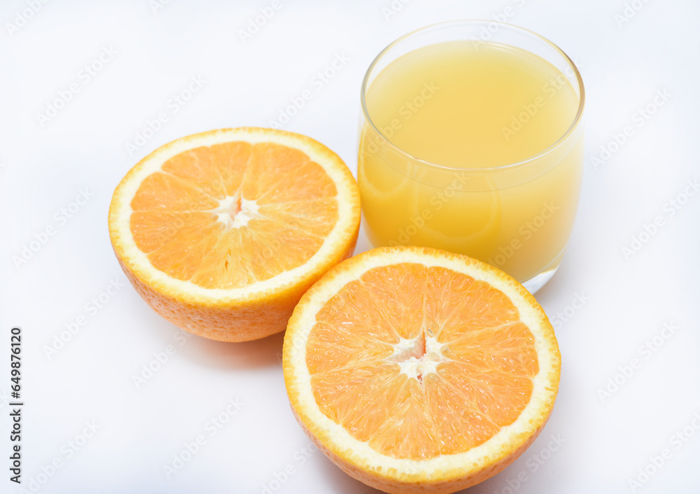 Fototapeta premium Orange juice in a glass glass and the fruit of oranges. Refreshing drink on a white background of fruit.