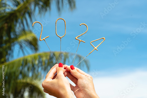 Numbers 2024 for the upcoming New Year in female hands in sunny weather against the background of the sky and palm trees