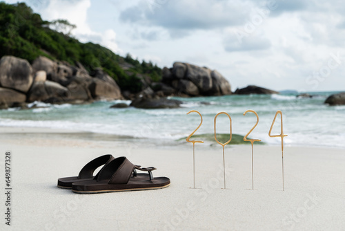 Numbers 2024 for the upcoming New Year on an empty sandy beach against the backdrop of waves and rocks