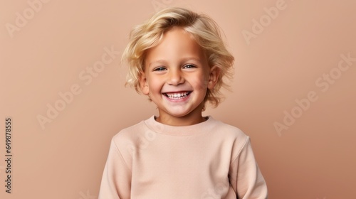 a blond-haired boy against a light beige background, radiating positivity.