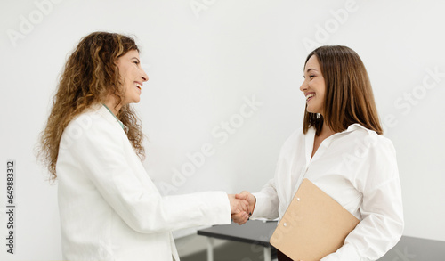 Two Smiling Businesswomen Meeting And Shaking Hands At Modern Office