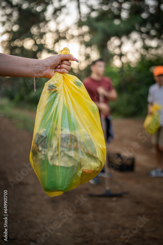 hands of unknown friends pick up waste garbage to clean forest