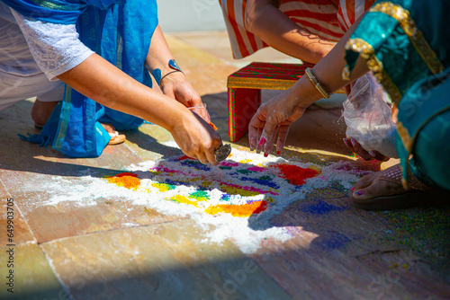 Colorful sand is arranged on the floor during the traditional sand ceremony at an Indian wedding