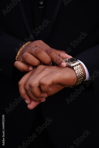 Closeup shot of a man with black suit checking time on his watch