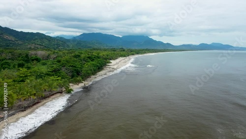 Captivating Drone Footage of Tropical Coastline Journey – Soaring Over Palm Trees and Rugged Mountains on the Left, Azure Sea Stretching to the Horizon on the Right photo