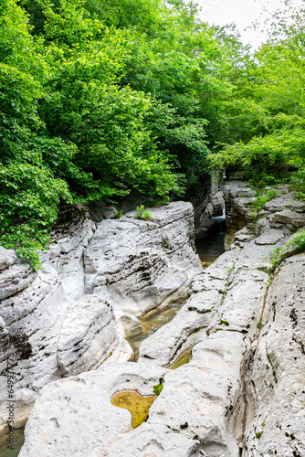 Massive chalk stones riverbed with wild river and pools formed by Okatse Waterfall in gorge of Satsikvilo, lush vegetation, Georgia. photo