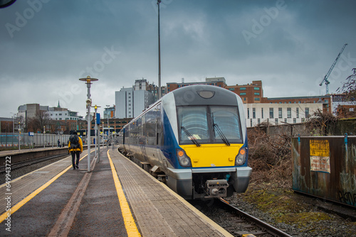Diesel train at the Great Victoria street station in Belfast, northern ireland. View towards the train track main office building on a cloudy day.
