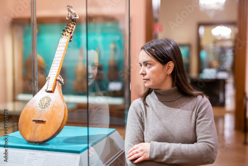 Portrait of interested adult brunette visiting exhibition of medieval musical instruments in historical museum .. photo