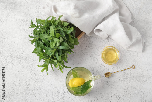 Cup of fresh mint tea with lemon and honey on grunge light table
