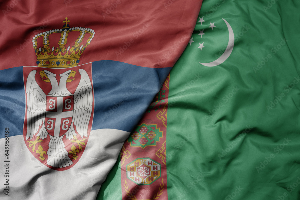 big waving national colorful flag of serbia and national flag of turkmenistan .
