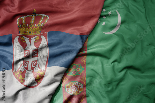 big waving national colorful flag of serbia and national flag of turkmenistan .