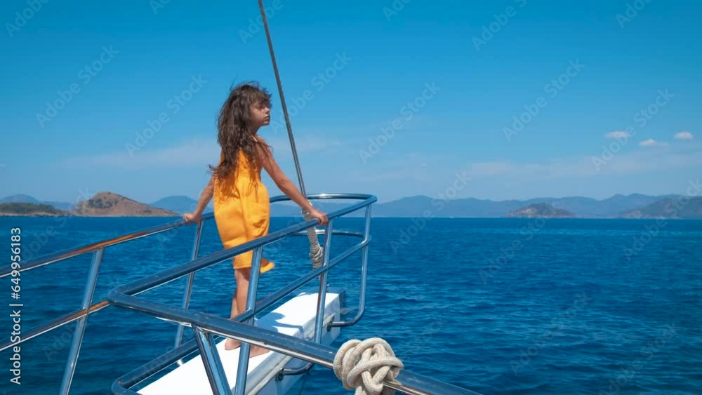 Child stand on yacht bow. A young sporty little girl relax on the boat bow and admire the blue sea in the sun light. Child stand on yacht bow. A young sporty little girl relax on the boat bow and admire the blue sea in the sun light.