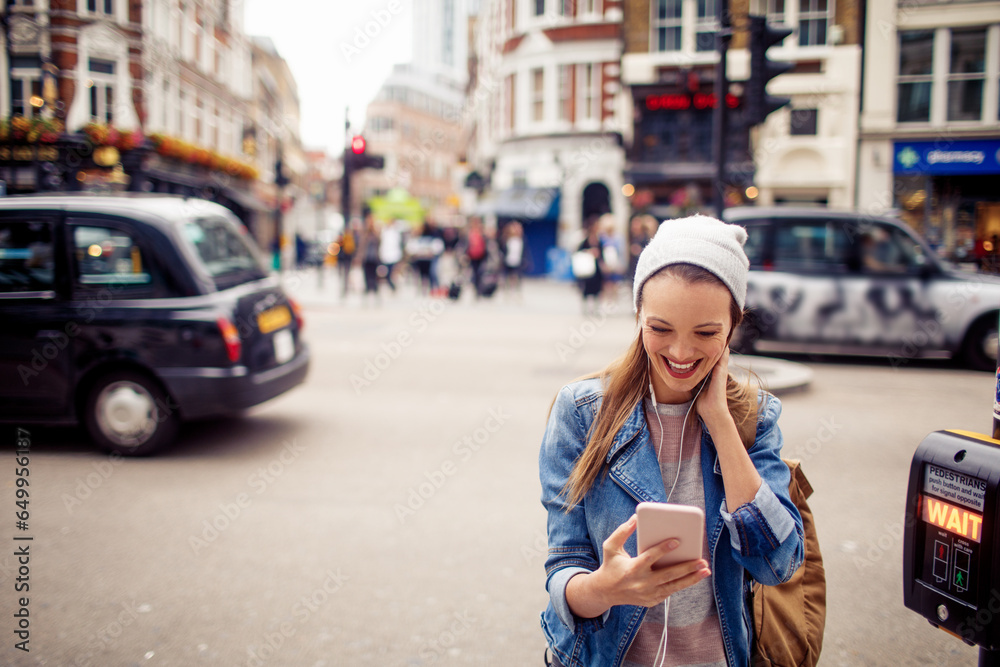 Young Caucasian woman using a smartphone while crossing the street in London UK