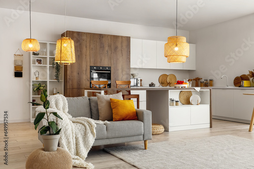Tableau sur toile Interior of modern open plan kitchen with island table, grey sofa and glowing la