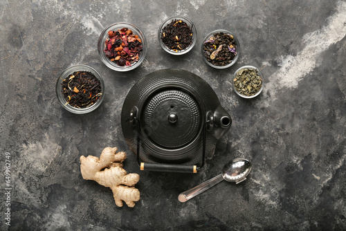 Composition with teapot, different types of tea and infuser on grunge background