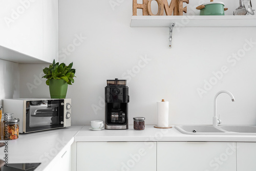 Interior of modern kitchen with coffee machine on white counter