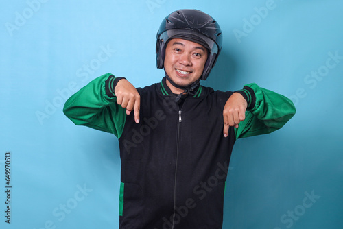 Cheerful young Asian male courier in safety helmet pointing finger below showing empty space for text or ads