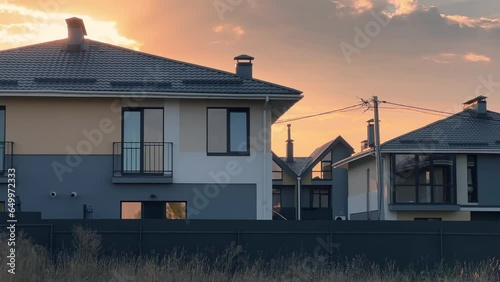 Newly built gated community with a group of homes and duplexes built together as a single development for sale in suburbia at summer sunset photo